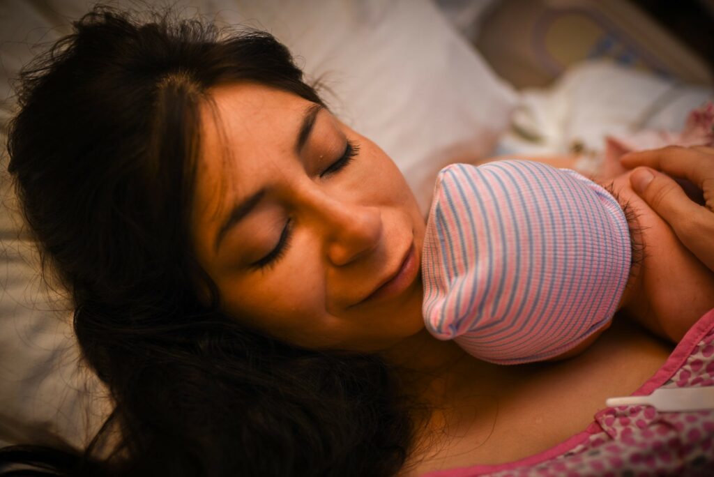 Image of Rainbow baby for Bone Broth for Post Partum care blog. Color close up image of mother with closed eyes, enjoying holding her baby skin to skin for the first time. Image courtesy of #dearbirth