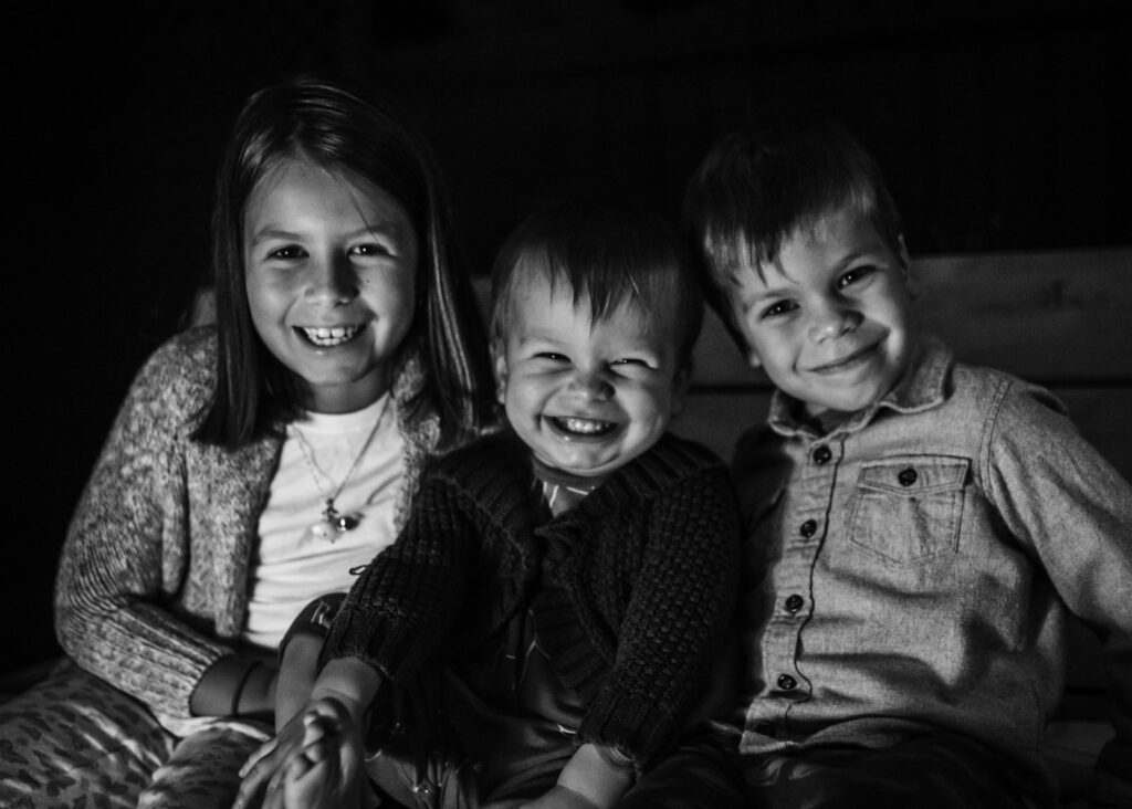 How to Write the Perfect Holiday Card: Black and white image of three children smiling at the camera captured in Los Angeles by Dear Birth