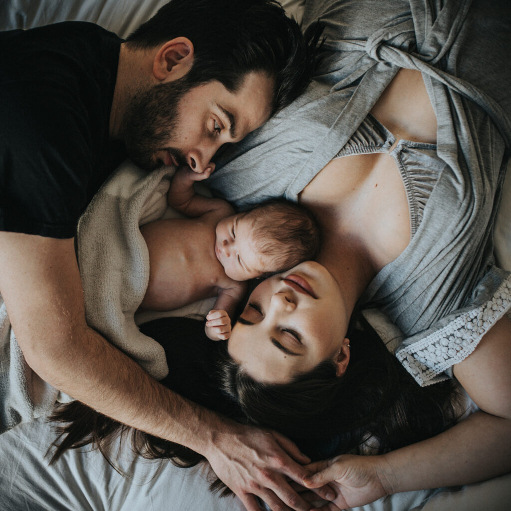 Color image of new family of three hugging on a bed during a fresh 48 newborn session with Los Angeles Birth Photographer Diana Hinek for ArtShaped Photography