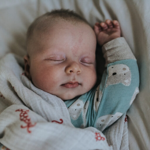 color image of newborn in pajamas with his arm up as photographed by Los Angeles Pregnancy & Newborn Birth Photographer Diana Hinek for Dear Birth
