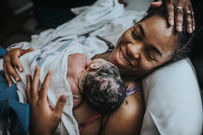 Hands of congratulations on thenew mother right after she births her baby as captured by Los Angeles Birth photographer and videographer Diana Hinek for Dear Birth