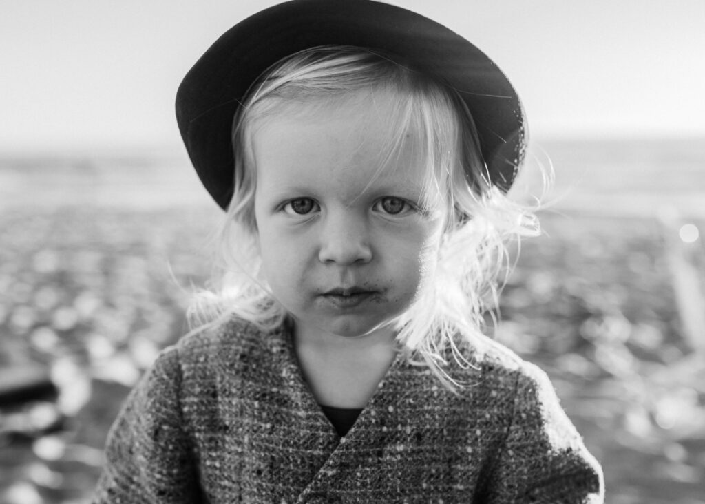 Black and white image of toddler wearing a hat as portrayed by Los Angeles Santa Monica family Photographer Diana Hinek