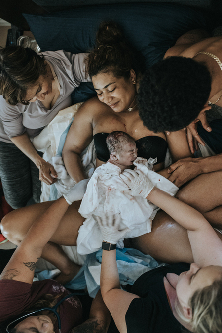 Top view of the birth of a baby as he is put on mother's chest right after by, captured by Los Angeles Birth Photographer and VIdeographer Dear Birth