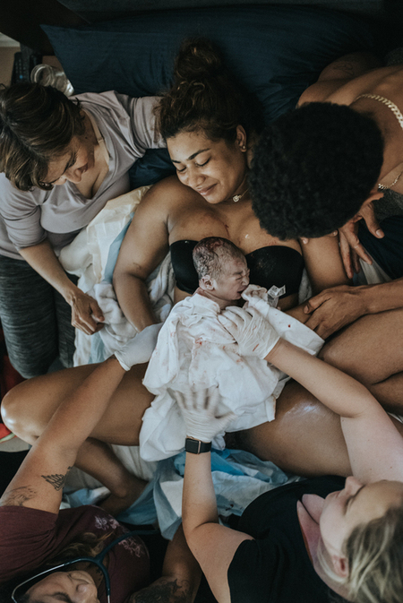 Color image from the birth galleries of the home birth of a family, right after the birth of their first baby brought on mother's chest by the hands of the midwives. Image courtesy of Los Angeles birth photographer Diana Hinek for #dearbirth. Visit www.dearbirth.com to 