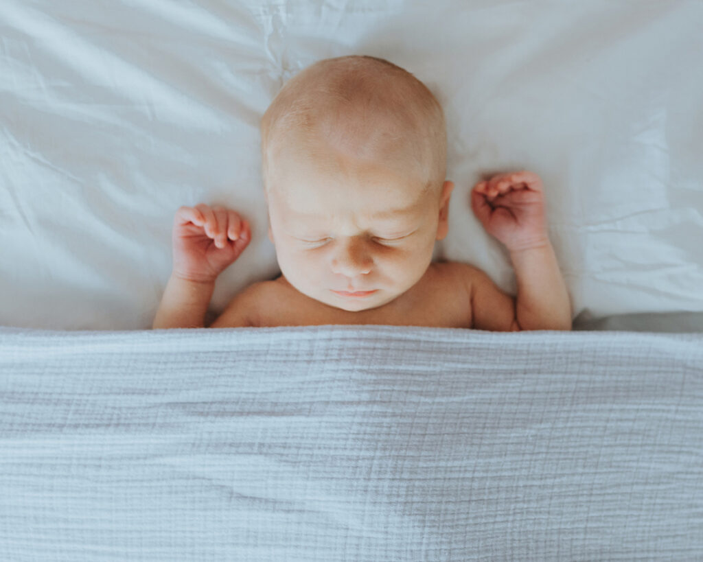 Baby-sleeps-arms-up-under-blanket